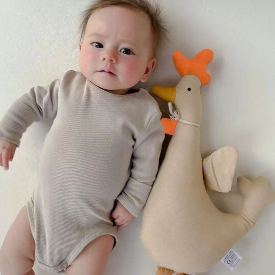 bébé allongé près doudou coq