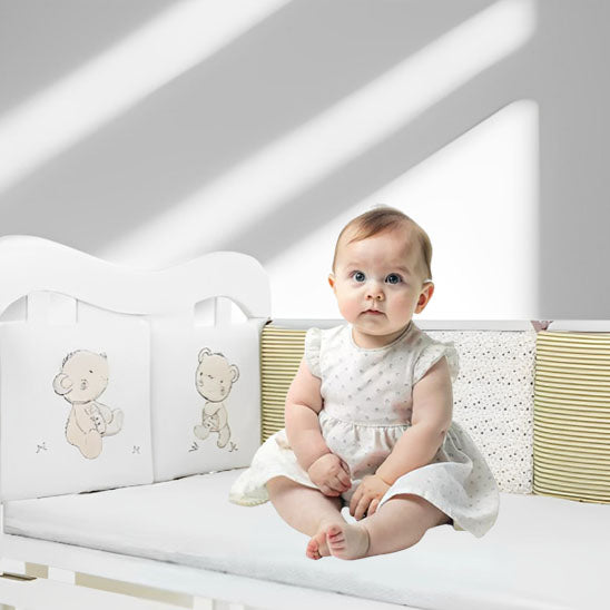 bébé assis dans lit avec tour de lit bébé
