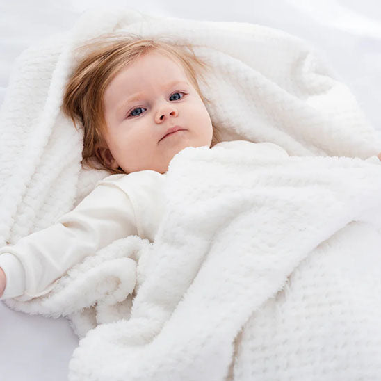 fillette dans sa couverture bébé blanche